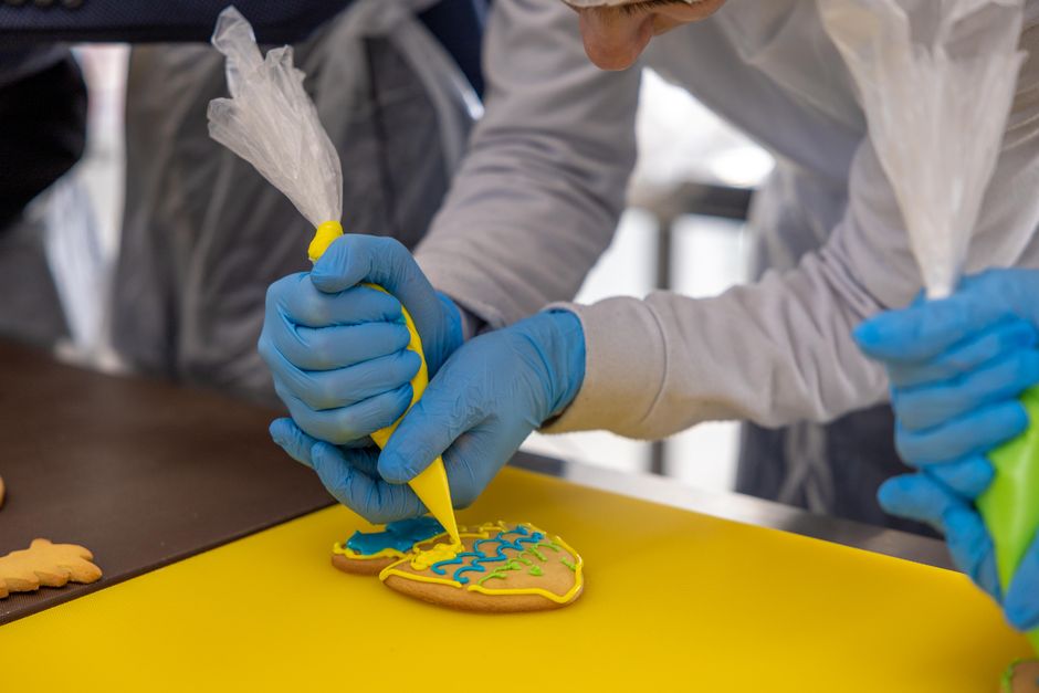 Hands decorating cookies with colorful icing, showcasing intricate designs.
